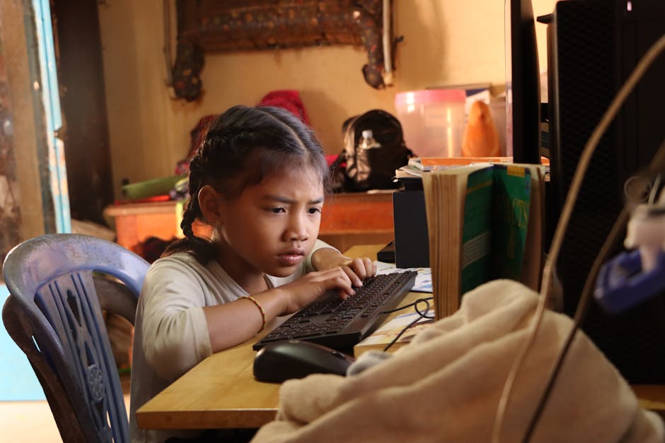 A young girl intently studying on a computer at home, embracing technology for education.
